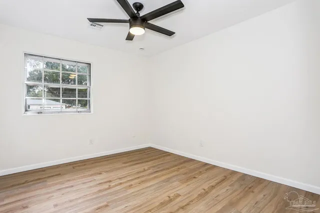 an empty room with wooden floor cabinet and ceiling fan