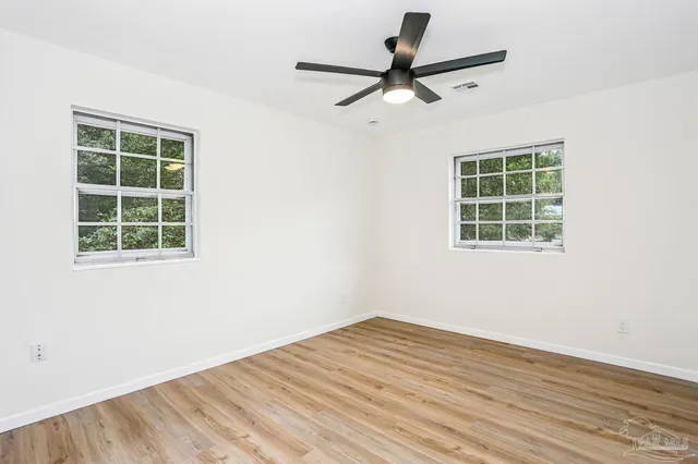 an empty room with a window and a ceiling fan