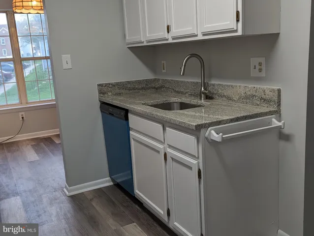 a kitchen with granite countertop a sink and dishwasher with wooden floor