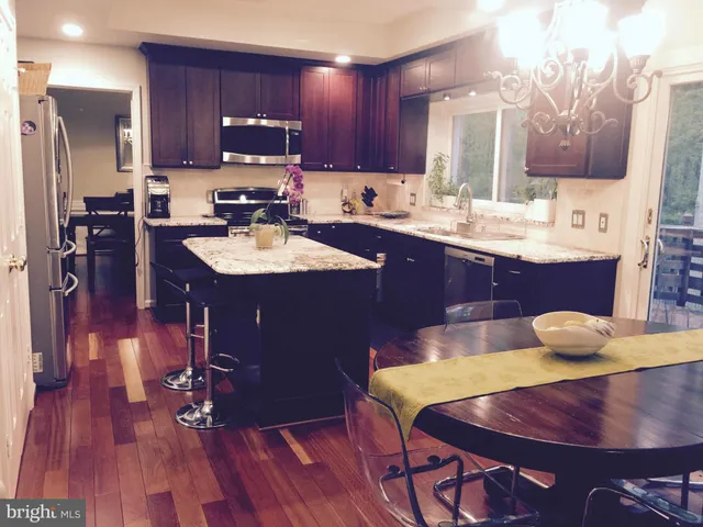 a kitchen with stainless steel appliances a dining table chairs and wooden floor