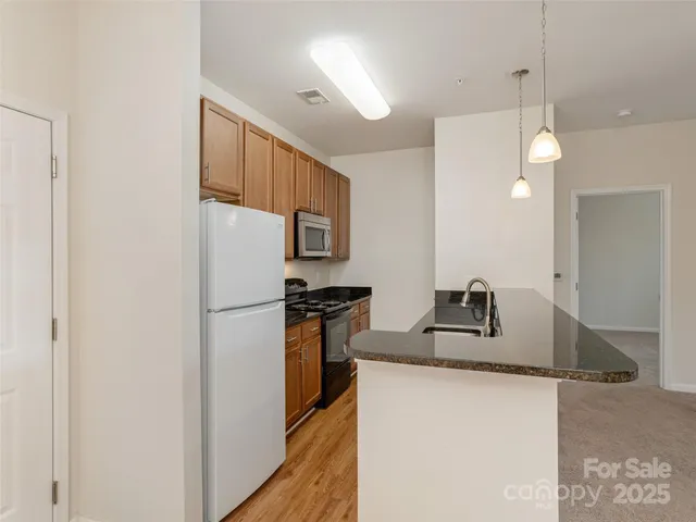 a kitchen with granite countertop a sink a refrigerator a stove a washer and dryer