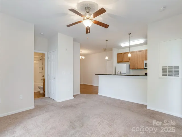 a view of an empty room and kitchen view