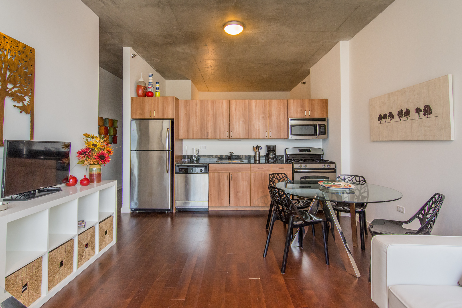 235 West Van Buren Street, Unit 1913 Chicago, IL 60607 - Photo 4 of 13 a kitchen with stainless steel appliances a white refrigerator a stove a sink a dining table and chairs with wooden floor