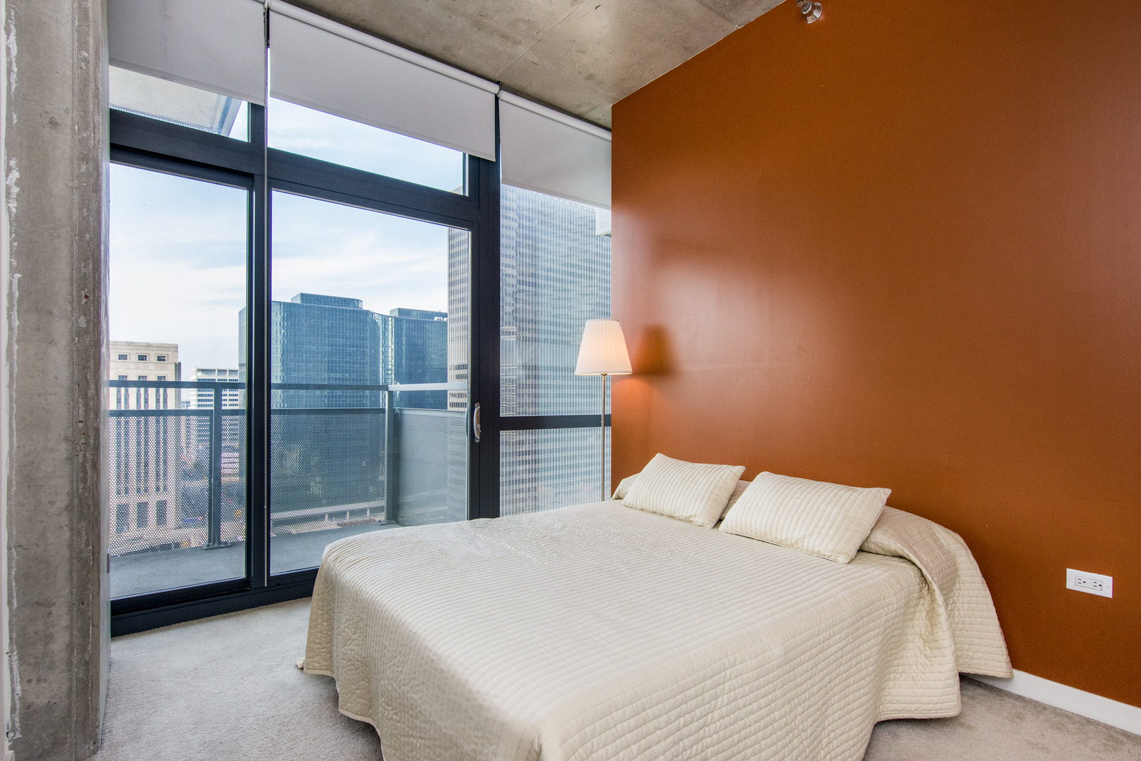 235 West Van Buren Street, Unit 1913 Chicago, IL 60607 - Photo 6 of 13 a bedroom with a large bed and a balcony next to a window