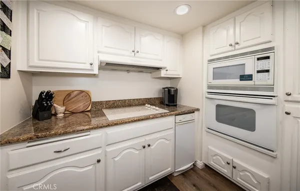 a kitchen with granite countertop white cabinets and white appliances