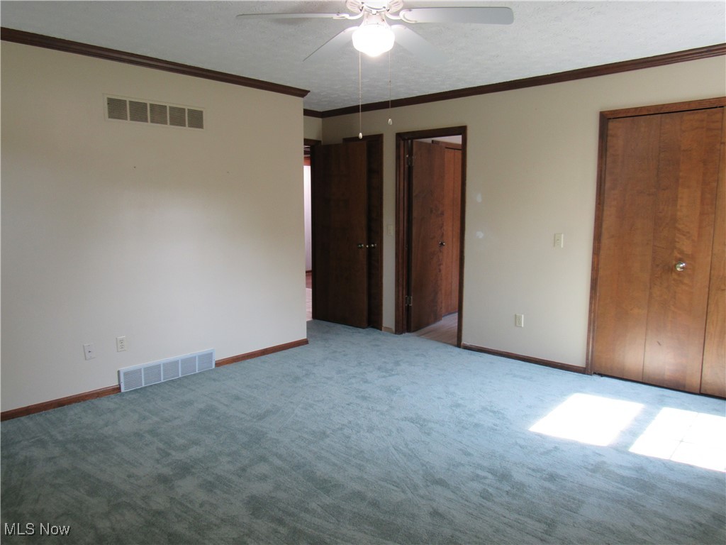 1120 Vincent Road Southeast North Canton, OH 44720 - Photo 35 of 50 Owner's bedroom featuring new carpet, ceiling fan, double closets and a textured ceiling
