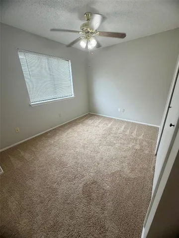 an empty room with windows and fan