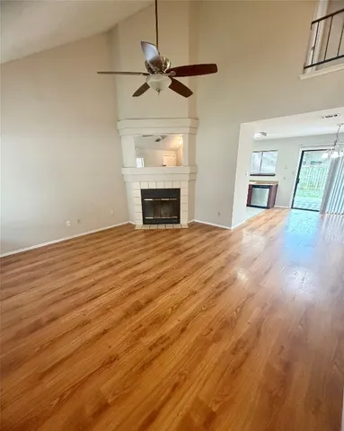 a view of an empty room with a fireplace and a ceiling fan