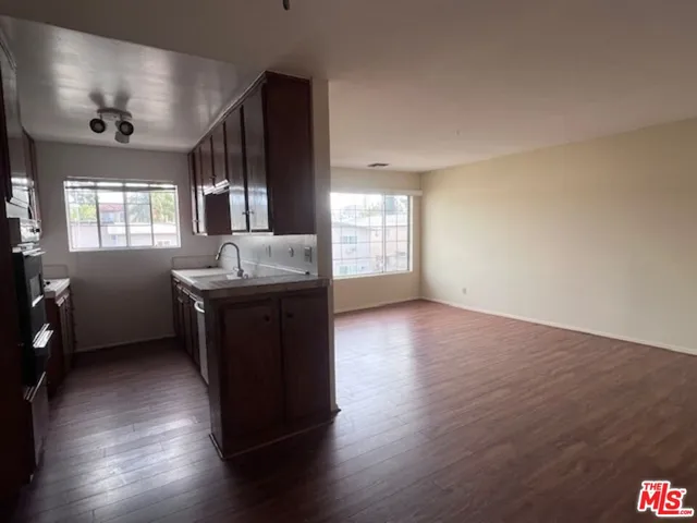 a living room with hard wood floors and a kitchen