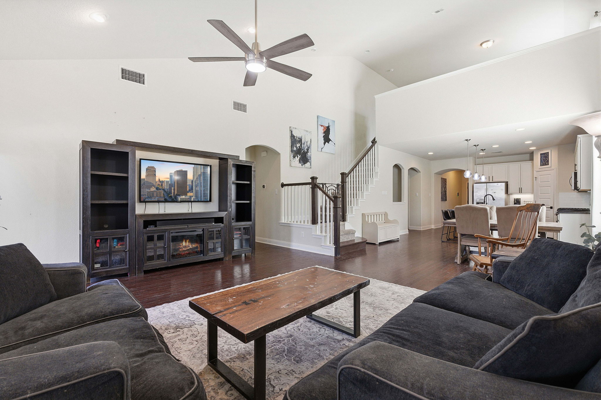 117 Methodius Drive Hutto, TX 78634 - Photo 6 of 40 Living room featuring wood finished floors, ceiling fan, a glass covered fireplace, arched walkways, and recessed lighting