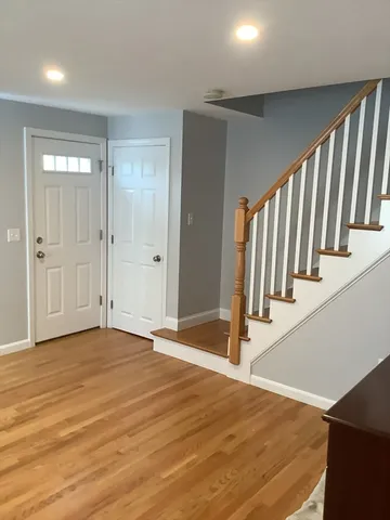 a view of an empty room with stairs and wooden floor