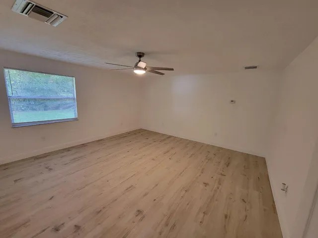 an empty room with a ceiling fan and window