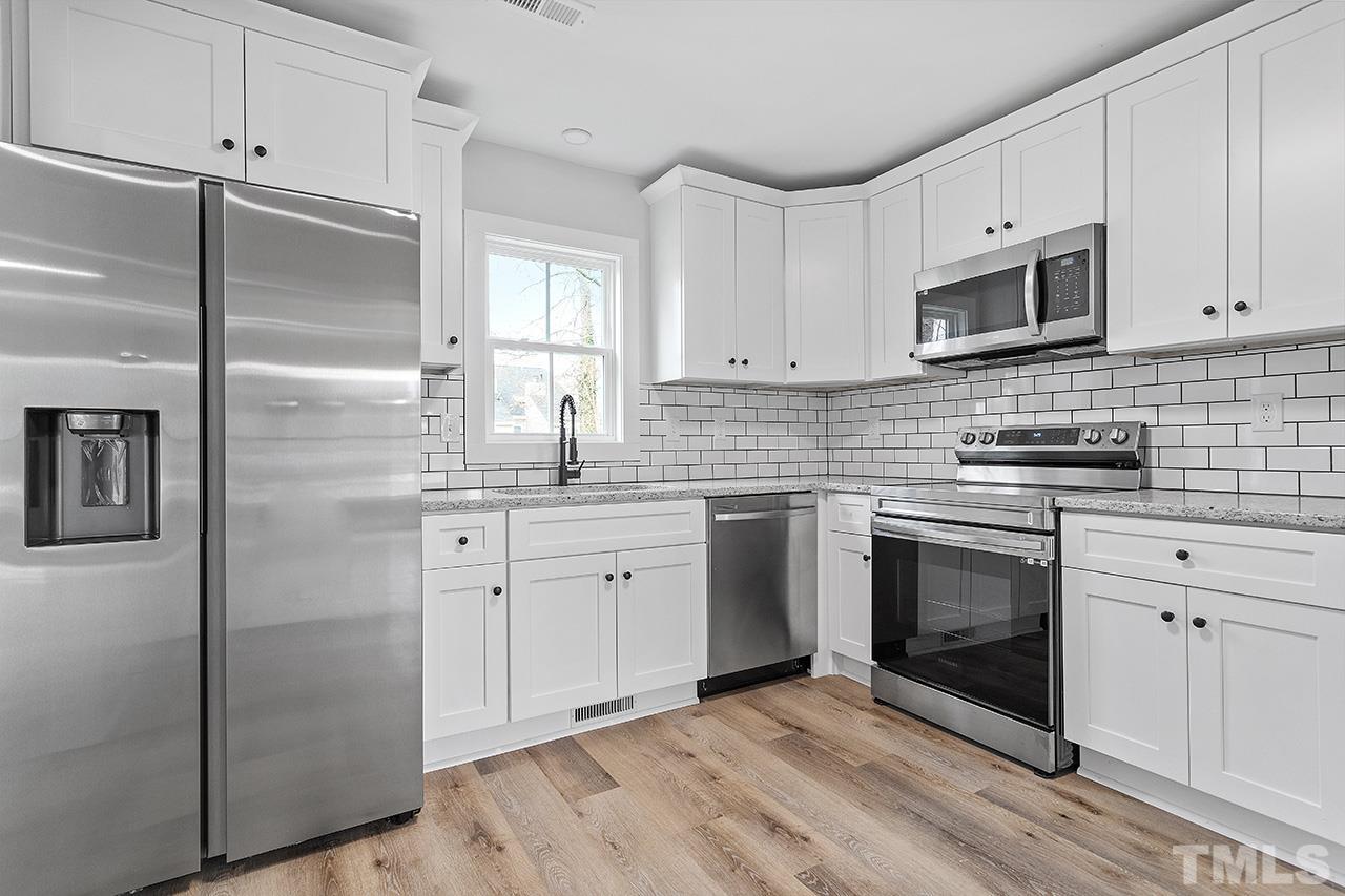 8205 Rocky Court Raleigh, NC 27616 - Photo 11 of 28 a kitchen with stainless steel appliances white cabinets a stove a sink and a refrigerator
