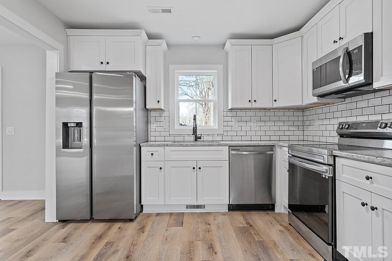 8205 Rocky Court Raleigh, NC 27616 - Photo 12 of 28 a kitchen with white cabinets stainless steel appliances a sink and a window