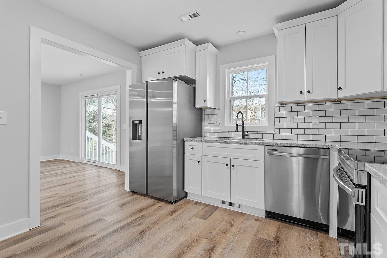 8205 Rocky Court Raleigh, NC 27616 - Photo 13 of 28 a kitchen with stainless steel appliances granite countertop a refrigerator a sink dishwasher a stove and white countertops with wooden floor