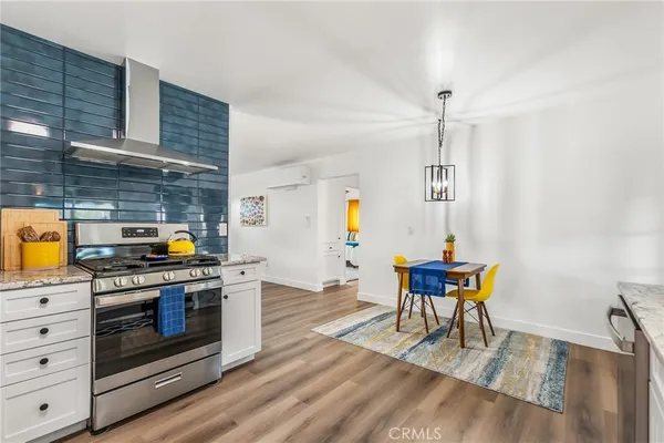a kitchen with stainless steel appliances wooden floor dining table and chairs