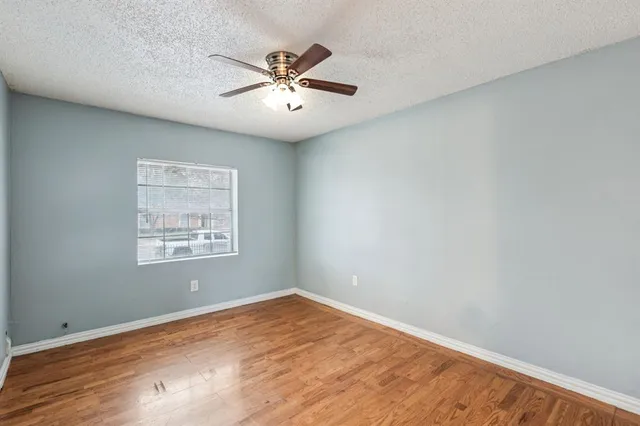 an empty room with wooden floor fan and windows