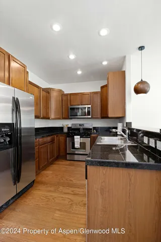 a kitchen with stainless steel appliances granite countertop a sink a stove and a refrigerator