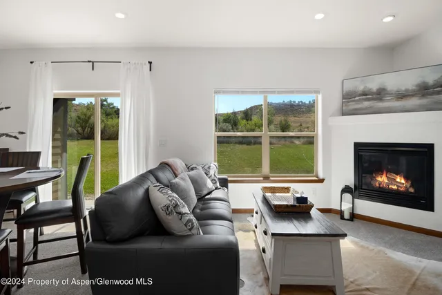 a living room with furniture a fireplace and a large window