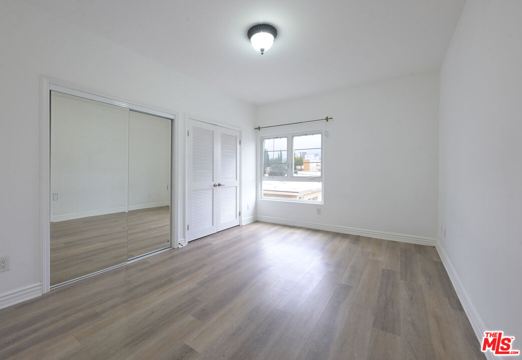 8555 Cashio Street, Unit PH4 Los Angeles, CA 90035 - Photo 12 of 43 an empty room with wooden floor and windows