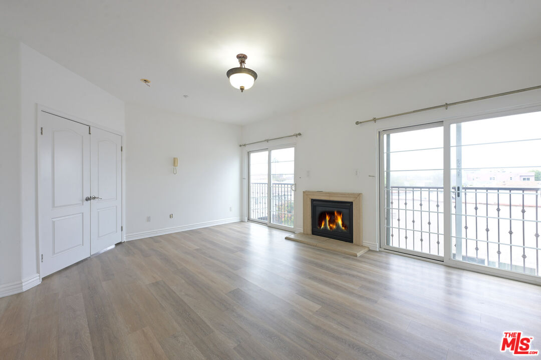 8555 Cashio Street, Unit PH4 Los Angeles, CA 90035 - Photo 17 of 43 an empty room with fireplace wooden floor and windows
