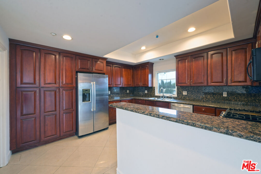8555 Cashio Street, Unit PH4 Los Angeles, CA 90035 - Photo 25 of 43 a kitchen with stainless steel appliances granite countertop wooden cabinets a refrigerator and a sink