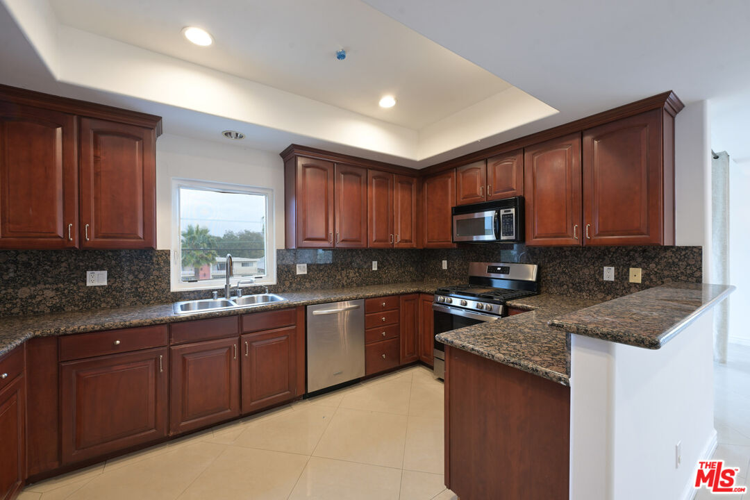 8555 Cashio Street, Unit PH4 Los Angeles, CA 90035 - Photo 26 of 43 a kitchen with stainless steel appliances granite countertop wooden cabinets a stove top oven a sink and dishwasher