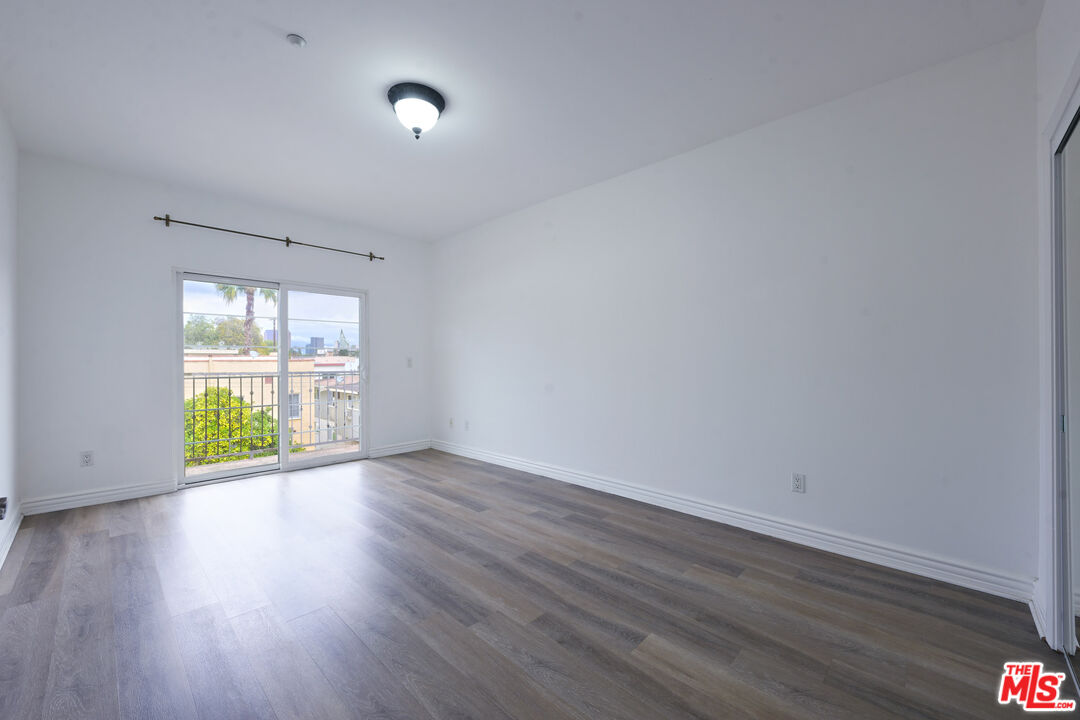 8555 Cashio Street, Unit PH4 Los Angeles, CA 90035 - Photo 42 of 43 a view of an empty room with wooden floor and a window