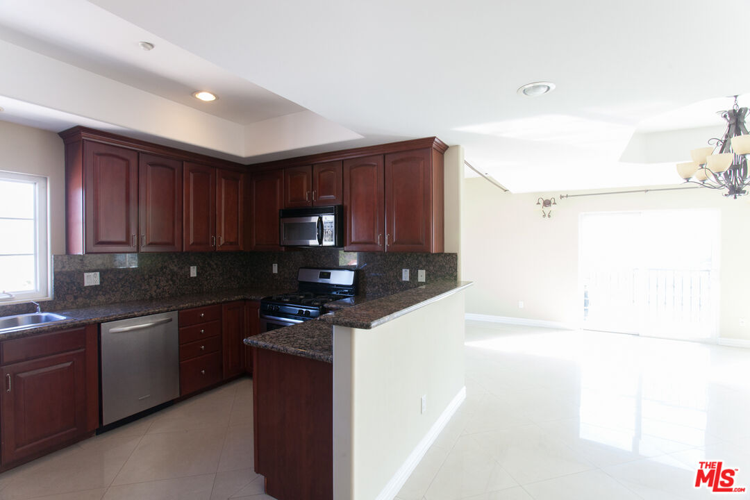 8555 Cashio Street, Unit PH4 Los Angeles, CA 90035 - Photo 7 of 43 a kitchen with granite countertop a sink a stove and cabinets