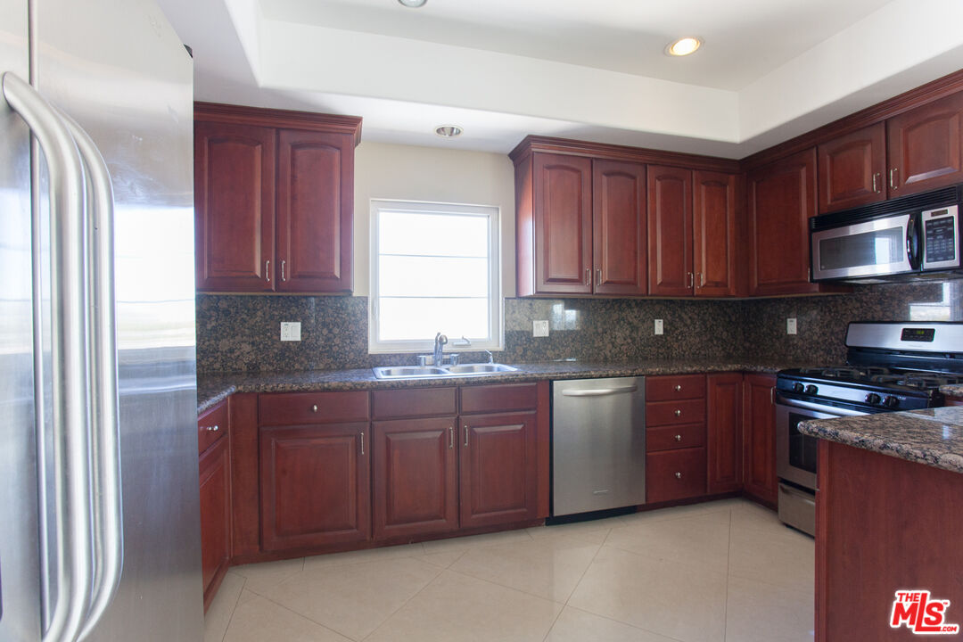 8555 Cashio Street, Unit PH4 Los Angeles, CA 90035 - Photo 8 of 43 a kitchen with stainless steel appliances granite countertop a stove sink and cabinets