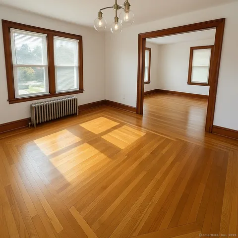 a view of an empty room with a window and wooden floor