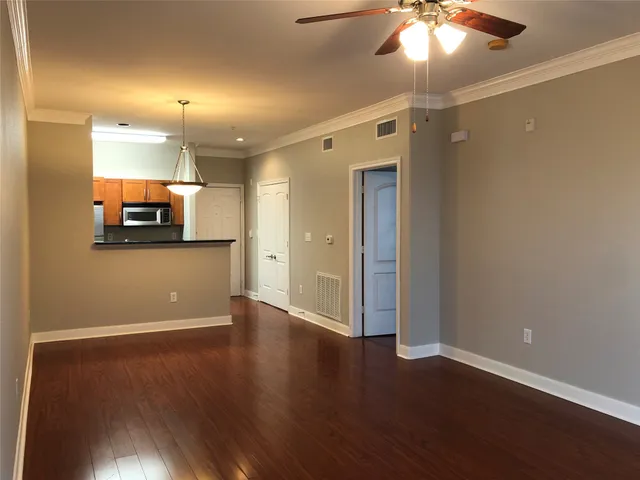 an empty room with wooden floor and a ceiling fan