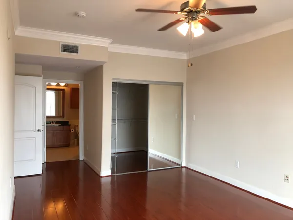 an empty room with wooden floor closet and windows