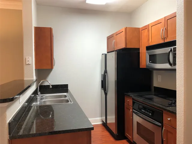 a kitchen with granite countertop a refrigerator stove and microwave
