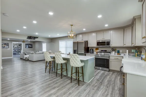 a kitchen with stainless steel appliances a refrigerator a sink dishwasher a stove and white cabinets with wooden floor