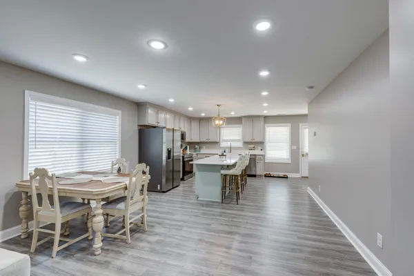 a kitchen with stainless steel appliances granite countertop a sink a stove top oven a refrigerator cabinets and a window