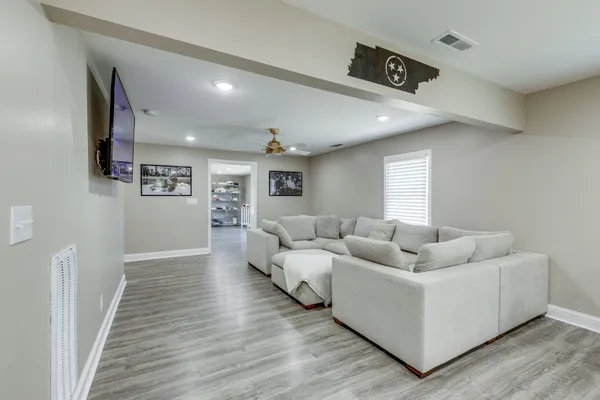 a living room with couches and kitchen view with wooden floor