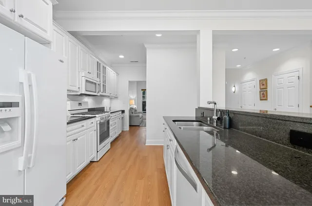 a large white kitchen with stainless steel appliances granite countertop a lot of counter space and a sink