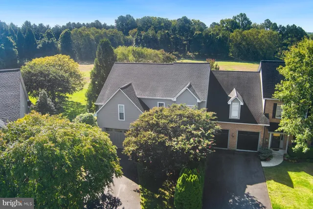 an aerial view of a house with a yard and a large tree