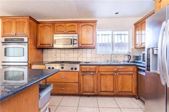 a kitchen with granite countertop a stove cabinets and refrigerator