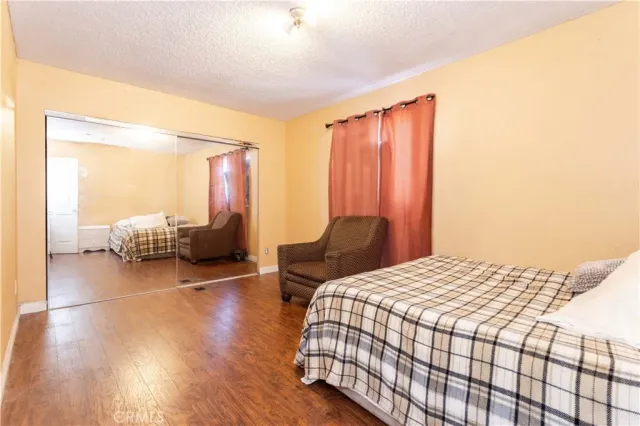 a bedroom with a bed and a couch with wooden floor
