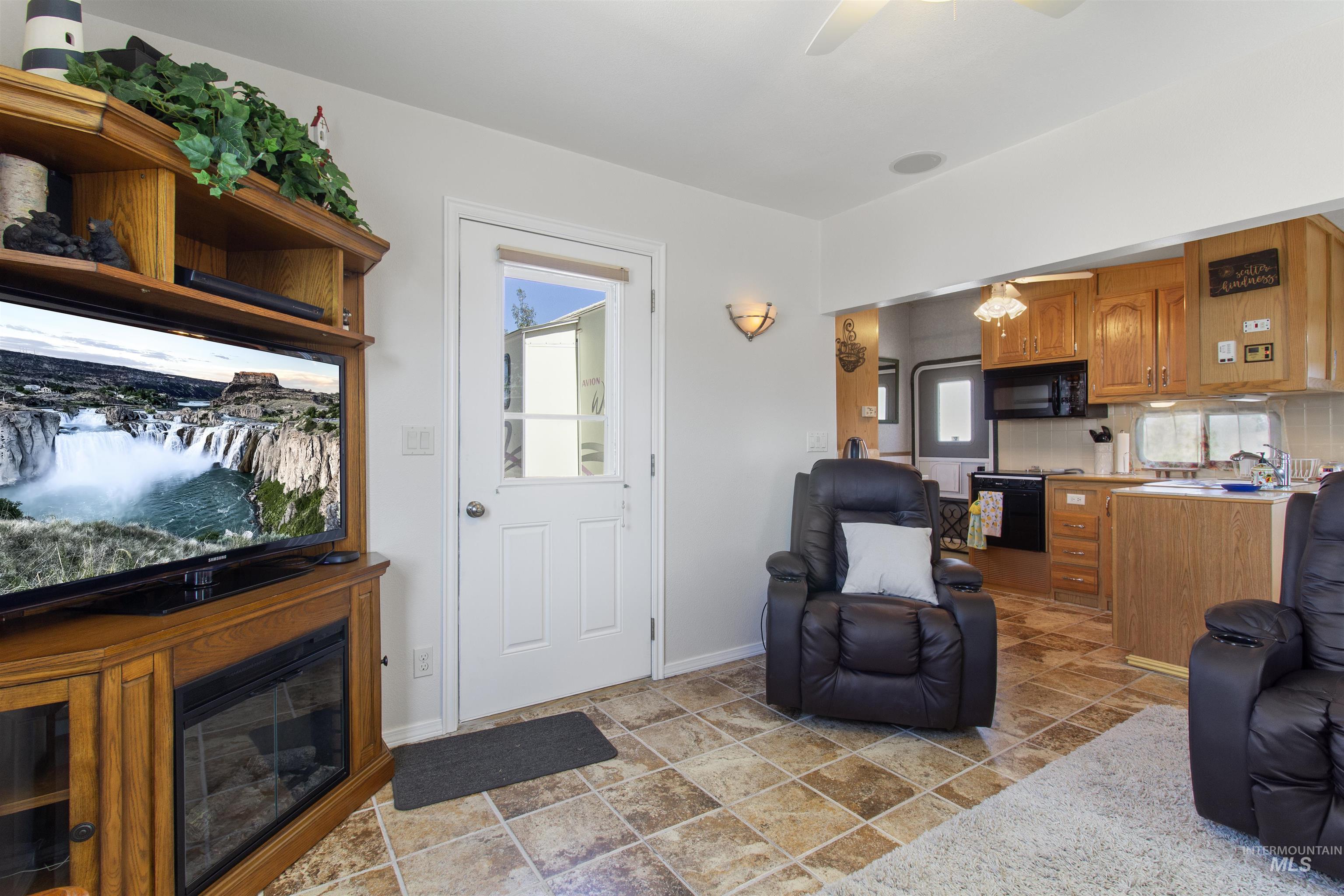 106 West Magic Road Shoshone, ID 83352 - Photo 6 of 45 Living area featuring a corner media console with an integrated electric fireplace, light-colored walls, and a ceiling fan