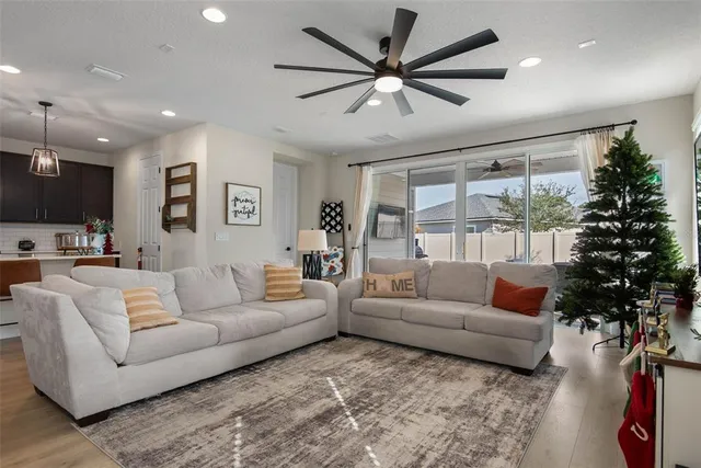 a living room with furniture ceiling fan and a large window