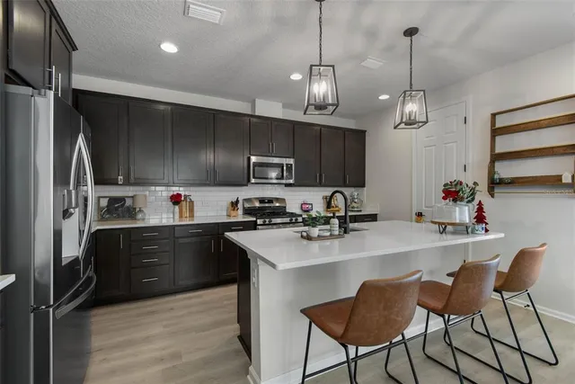 a kitchen with stainless steel appliances granite countertop a sink refrigerator and cabinets