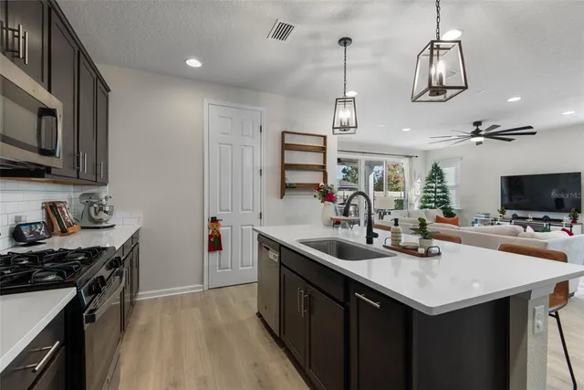 a kitchen with a stove a sink dishwasher a kitchen island with wooden cabinets and floor