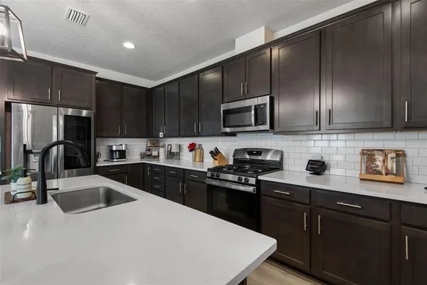 a kitchen with a sink a stove a refrigerator cabinets and a kitchen island