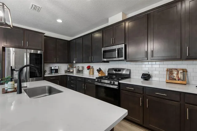 a kitchen with a sink a stove a refrigerator cabinets and a kitchen island
