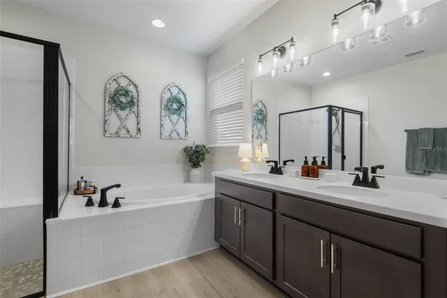 a bathroom with a double vanity sink mirror and bathtub