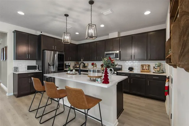 a kitchen with refrigerator a stove and chairs