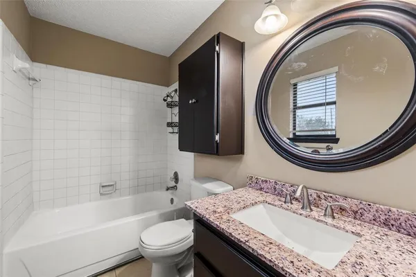 a bathroom with a granite countertop toilet a sink and a mirror